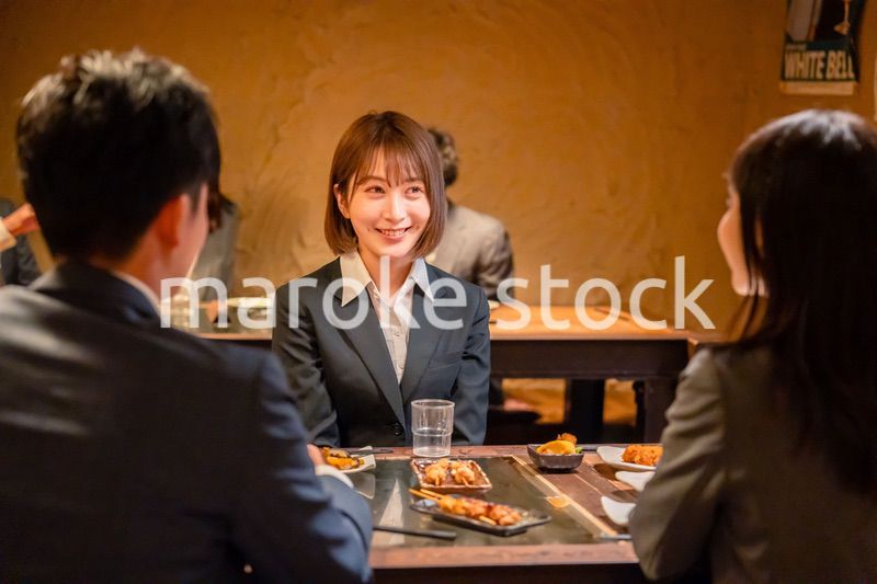 先輩社員と居酒屋で話をするフレッシュな女性