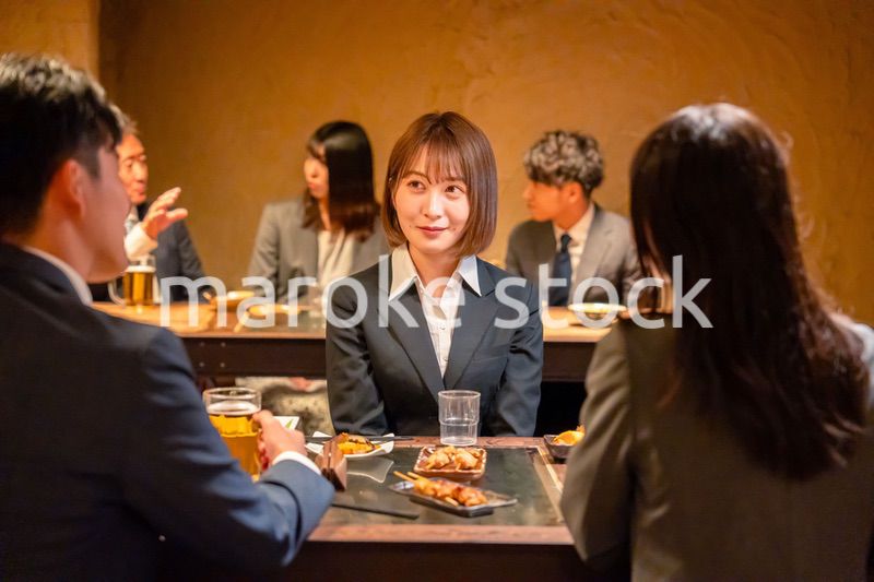 先輩社員と居酒屋で話をするフレッシュな女性
