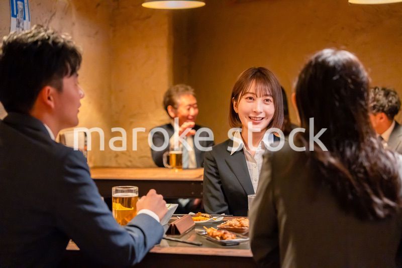 先輩社員と居酒屋で話をするフレッシュな女性