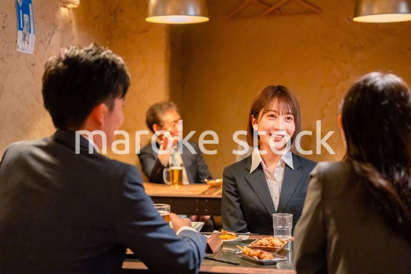 先輩社員と居酒屋で話をするフレッシュな女性