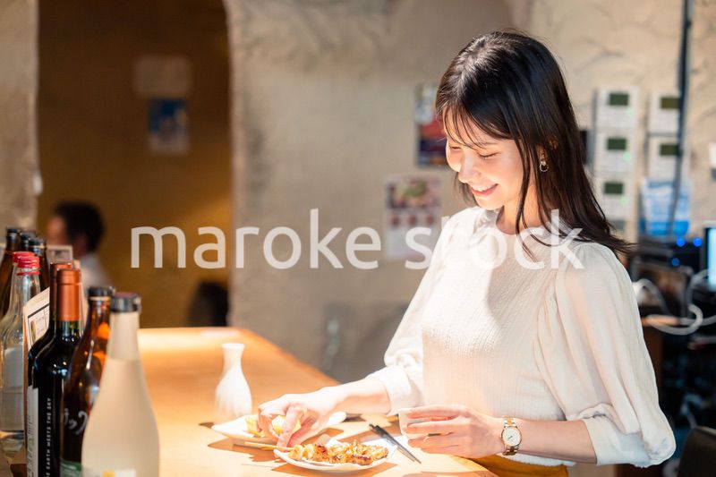 一人でカウンター席に座って焼き鳥を食べる女性