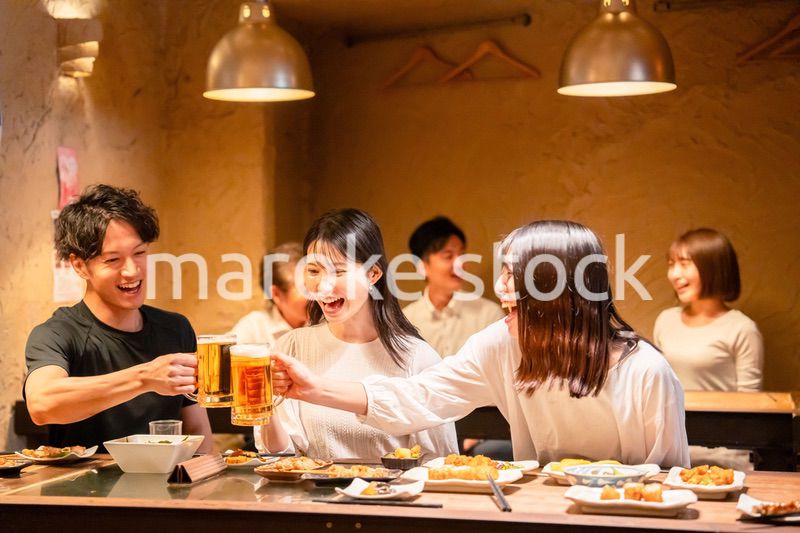 居酒屋でお酒を飲む若い男女