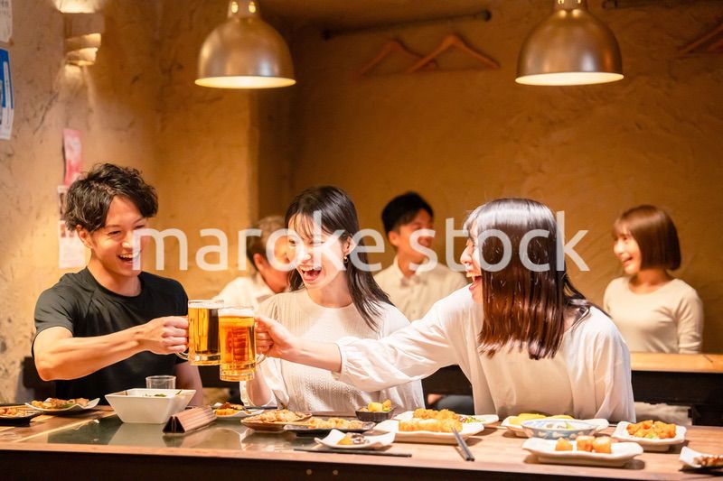 居酒屋でお酒を飲む若い男女