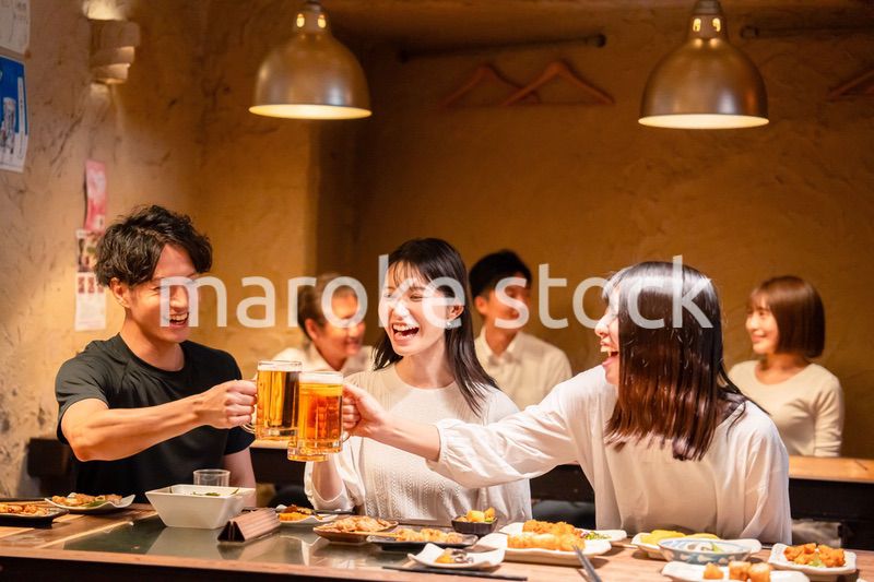 居酒屋でお酒を飲む若い男女