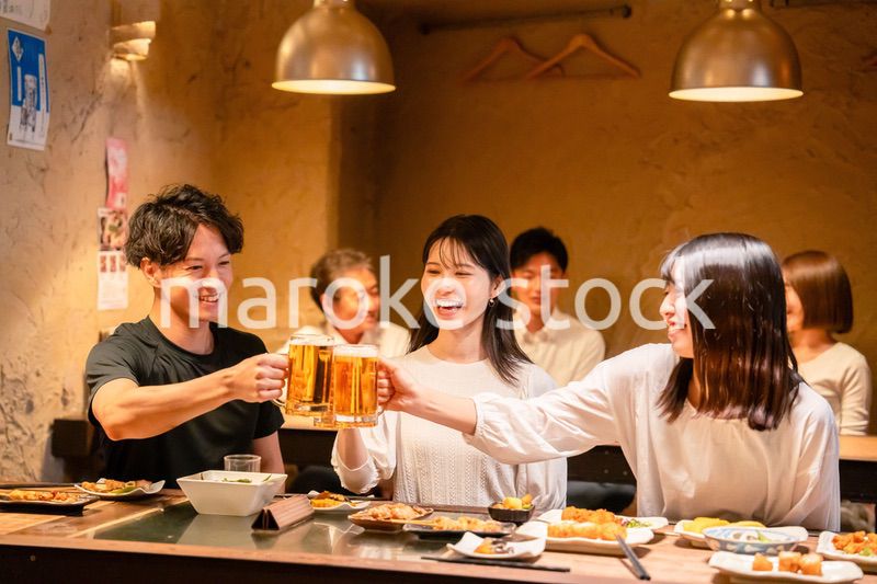 居酒屋でお酒を飲む若い男女