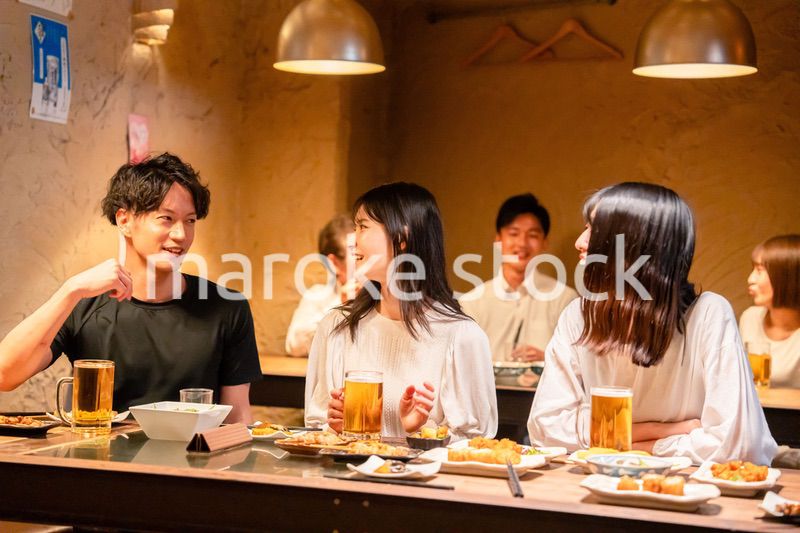 居酒屋でお酒を飲む若い男女