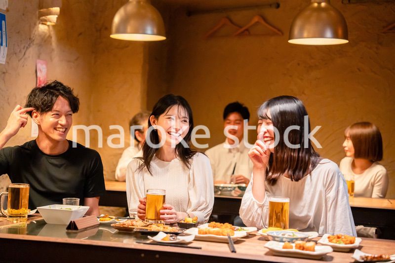 居酒屋でお酒を飲む若い男女