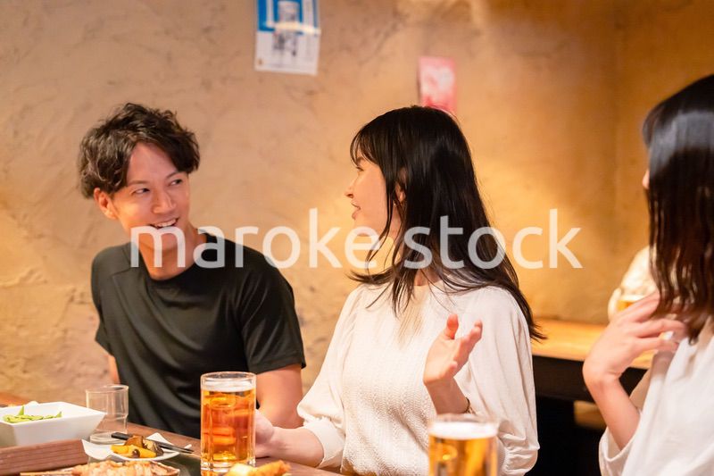 居酒屋でお酒を飲む若い男女