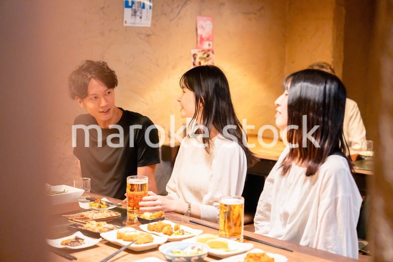 居酒屋でお酒を飲む若い男女