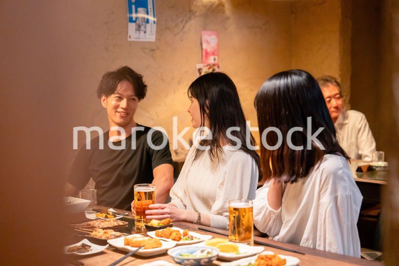 居酒屋でお酒を飲む若い男女