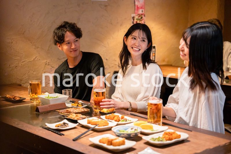 居酒屋でお酒を飲む若い男女