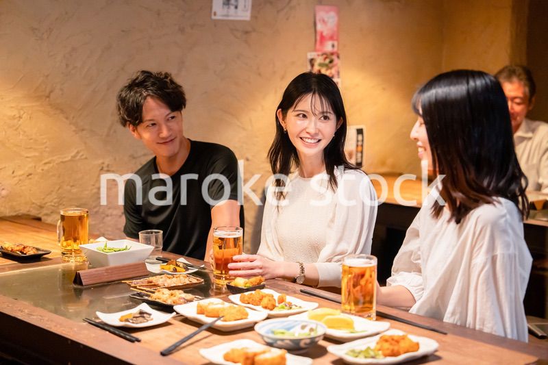 居酒屋でお酒を飲む若い男女