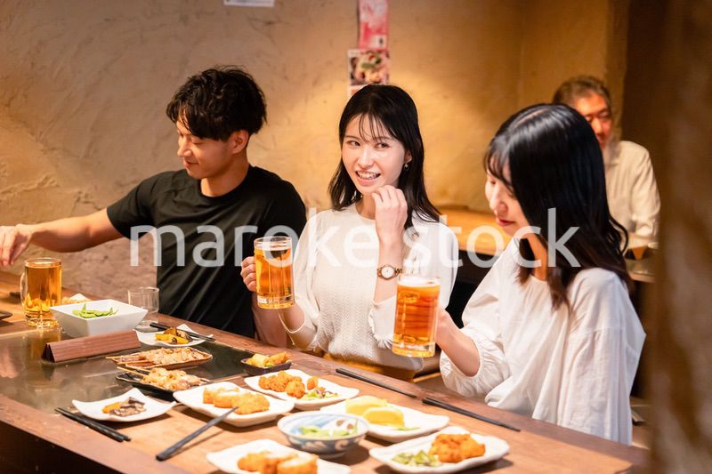 居酒屋でお酒を飲む若い男女