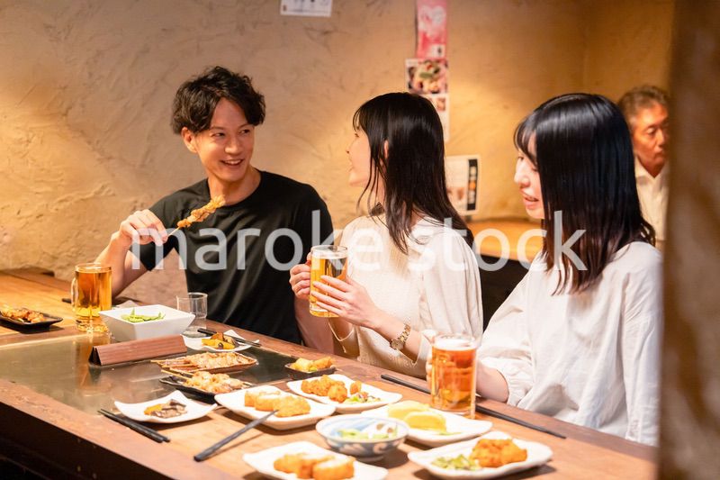 居酒屋でお酒を飲む若い男女