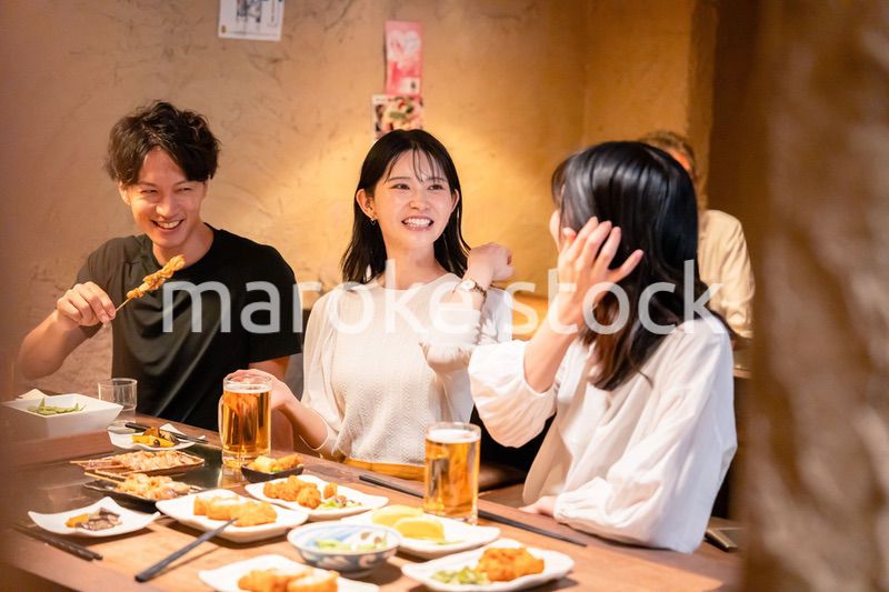 居酒屋でお酒を飲む若い男女