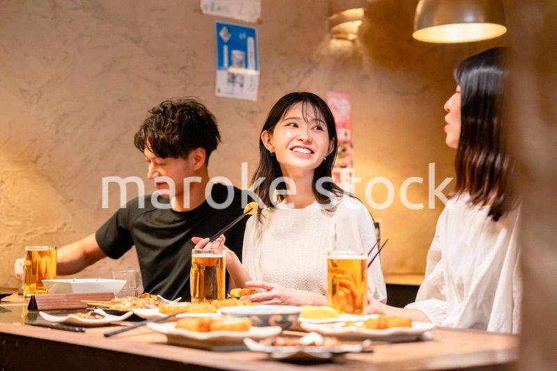 居酒屋でお酒を飲む若い男女