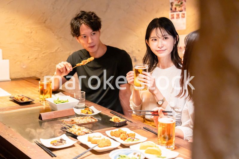居酒屋でお酒を飲む若い男女