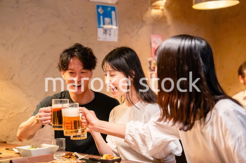 居酒屋でお酒を飲む若い男女