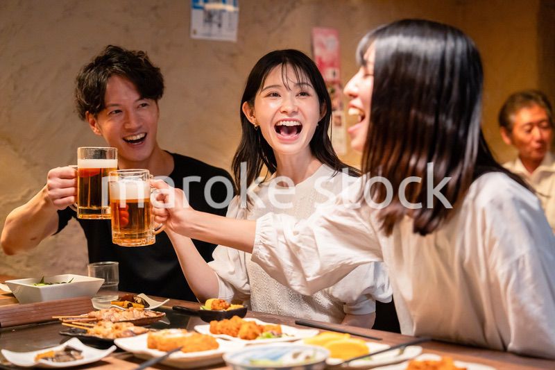 居酒屋でお酒を飲む若い男女