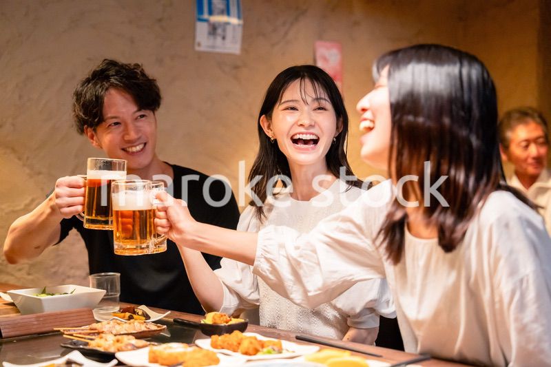 居酒屋でお酒を飲む若い男女