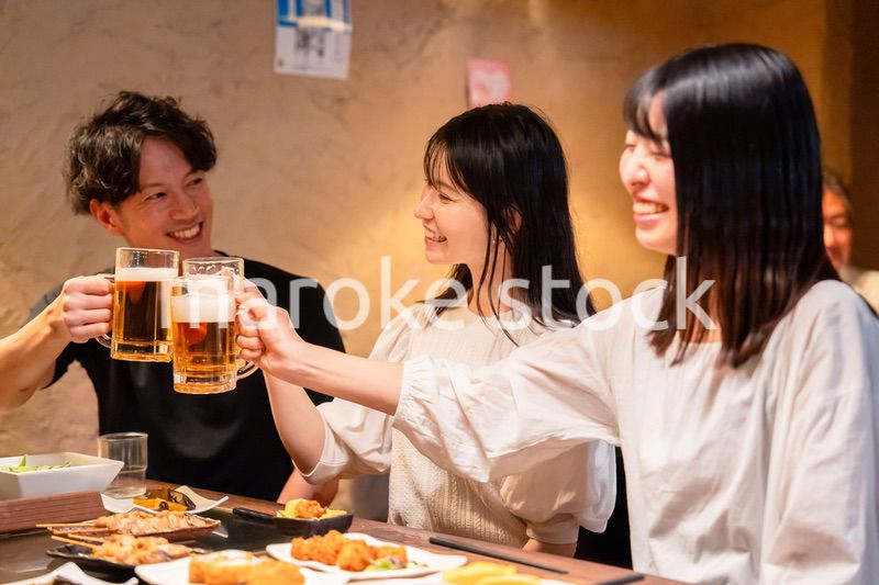居酒屋でお酒を飲む若い男女