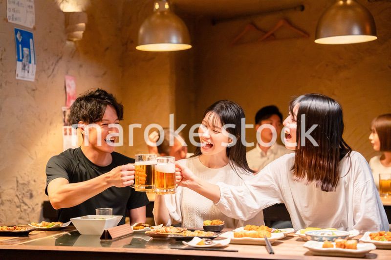 居酒屋でお酒を飲む若い男女