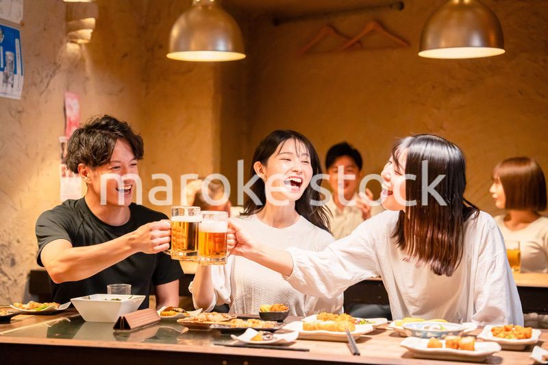 居酒屋でお酒を飲む若い男女
