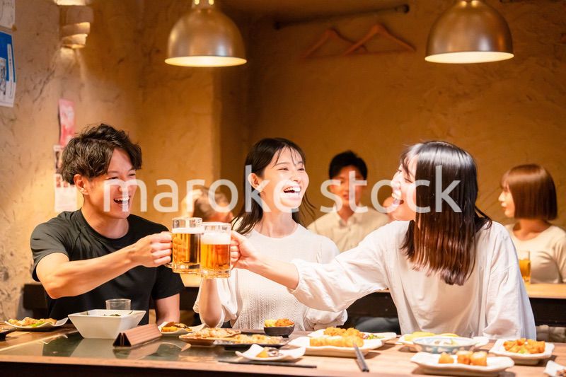 居酒屋でお酒を飲む若い男女