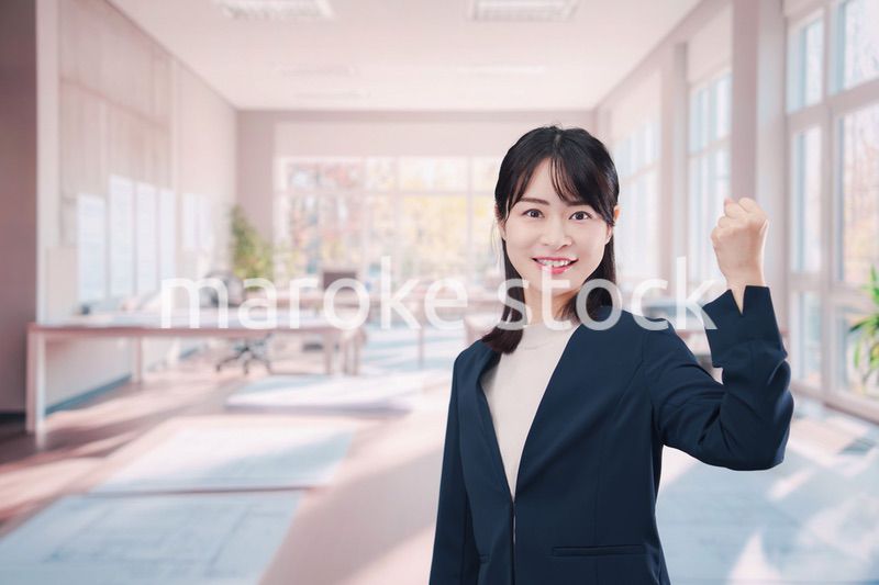 オフィスカジュアルでオフィスに立つ若い女性