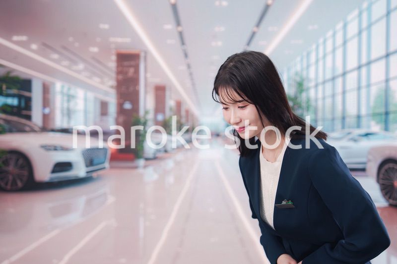 カーディーラーで接客をする若い女性
