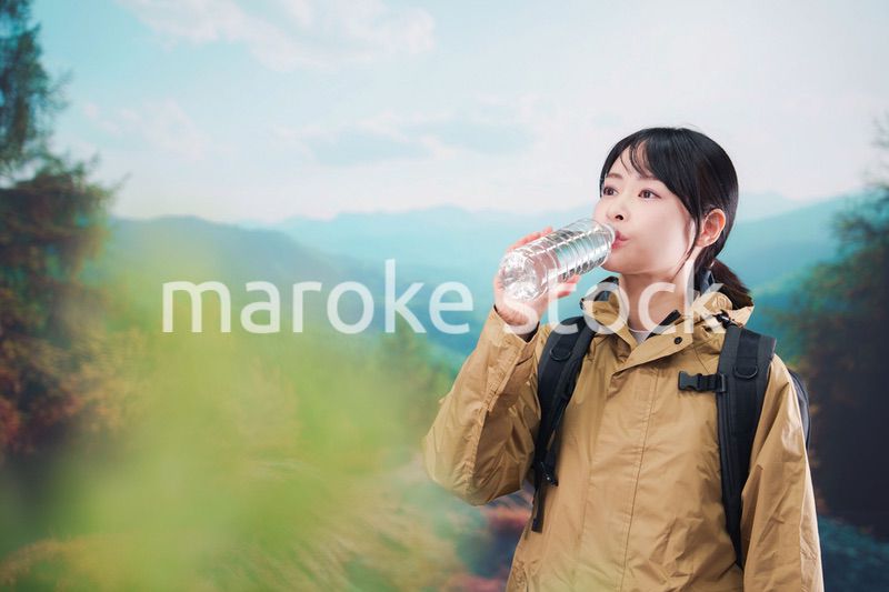 登山をしながら水分補給をする若い女性