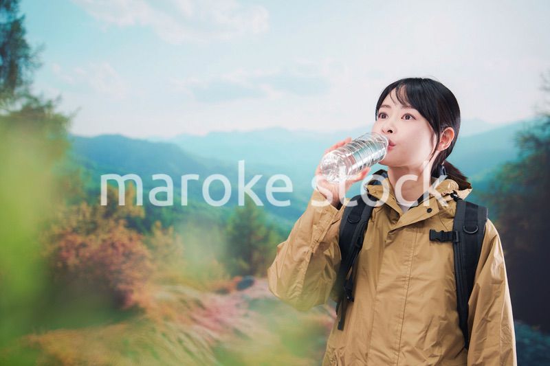 登山をしながら水分補給をする若い女性