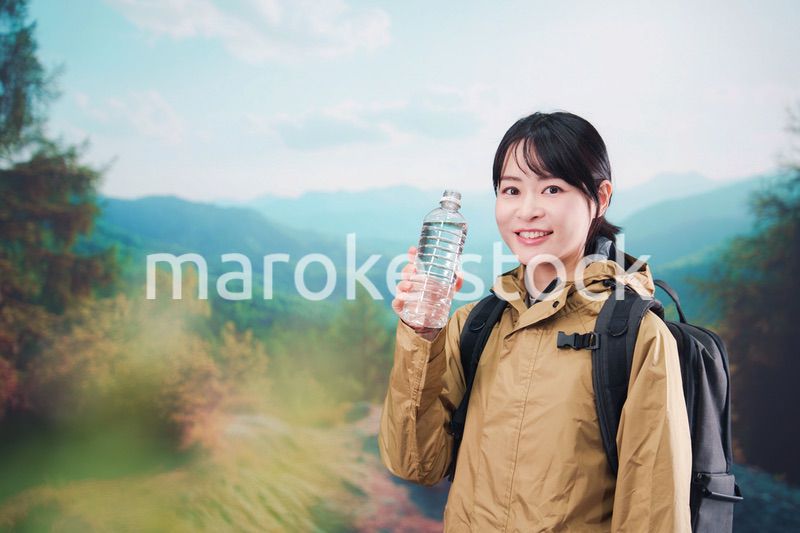 登山をしながら水分補給をする若い女性
