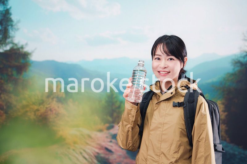 登山をしながら水分補給をする若い女性