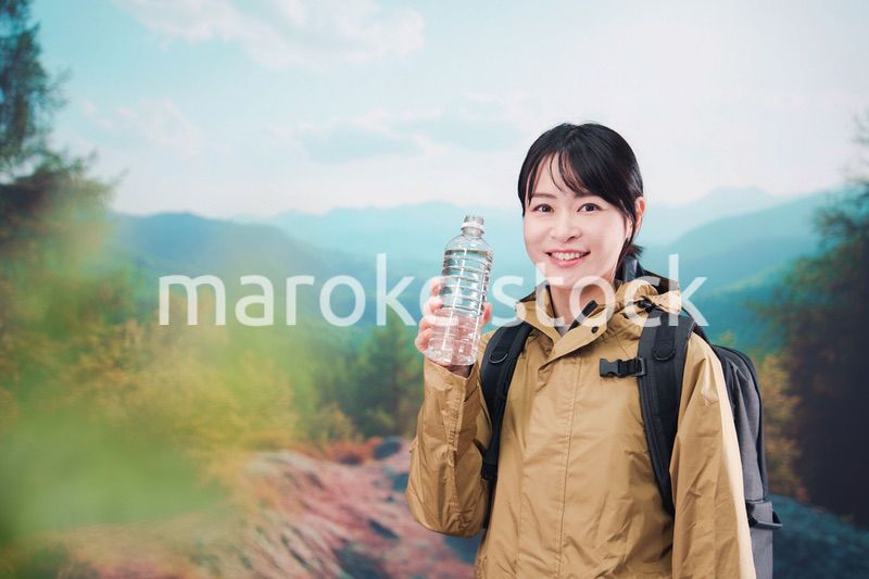 登山をしながら水分補給をする若い女性