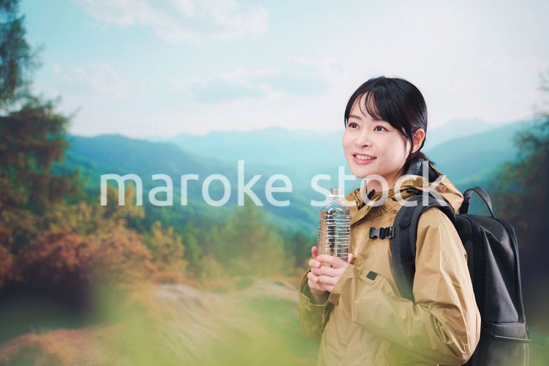 登山をしながら水分補給をする若い女性