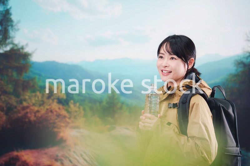 登山をしながら水分補給をする若い女性