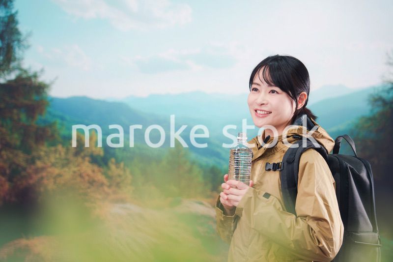 登山をしながら水分補給をする若い女性