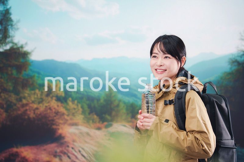 登山をしながら水分補給をする若い女性