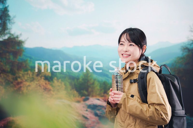登山をしながら水分補給をする若い女性