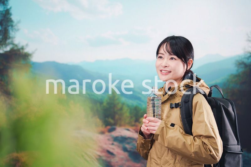 登山をしながら水分補給をする若い女性