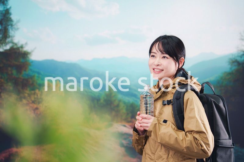 登山をしながら水分補給をする若い女性