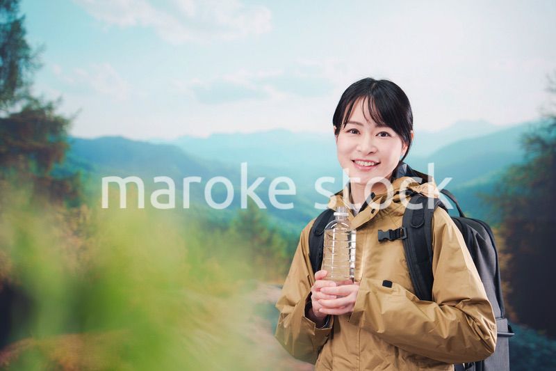 登山をしながら水分補給をする若い女性