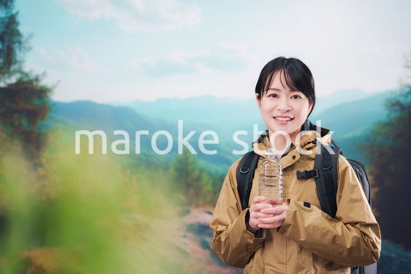 登山をしながら水分補給をする若い女性