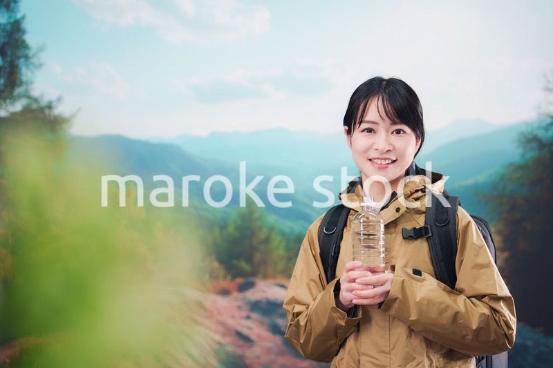 登山をしながら水分補給をする若い女性