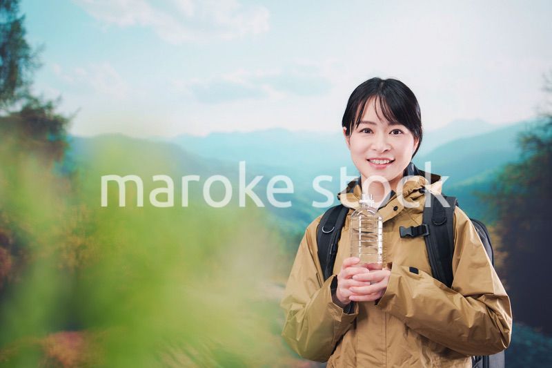 登山をしながら水分補給をする若い女性