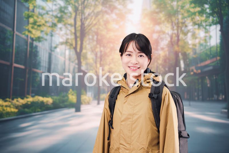 レインコートを着て通勤をする若い女性会社員