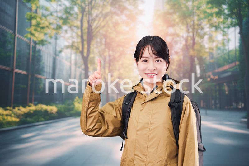 レインコートを着て通勤をする若い女性会社員