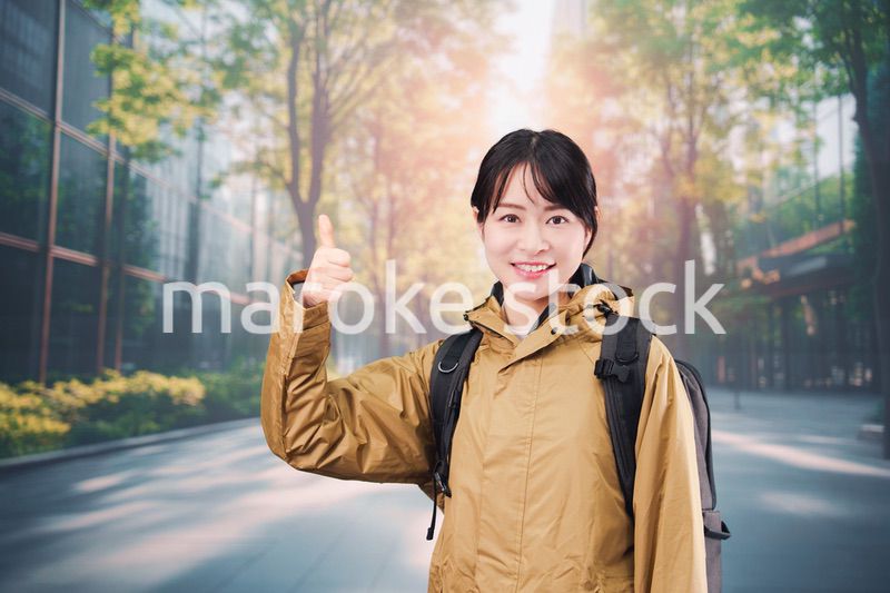 レインコートを着て通勤をする若い女性会社員