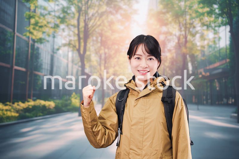 レインコートを着て通勤をする若い女性会社員